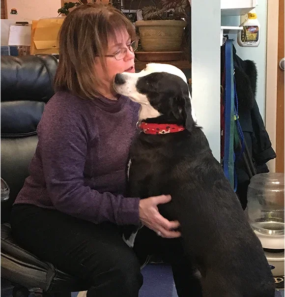 A woman and her black-and-white dog sharing a quiet moment.