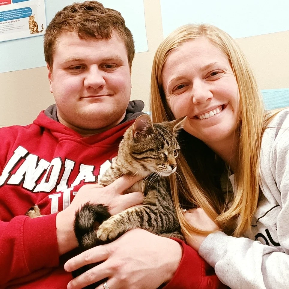 Two caregivers holding their tabby cat together at Highland.